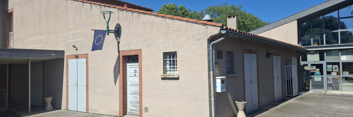 Bâtiment avec portes, fenêtres, drapeaux et lampadaires.