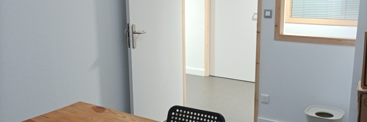 Pièce avec table en bois, chaises, porte, fenêtre et poubelle.