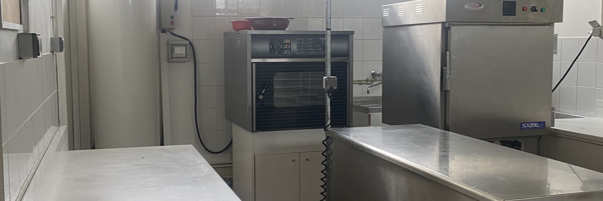 Cuisine professionnelle avec fours, réfrigérateurs, plans de travail et évier.