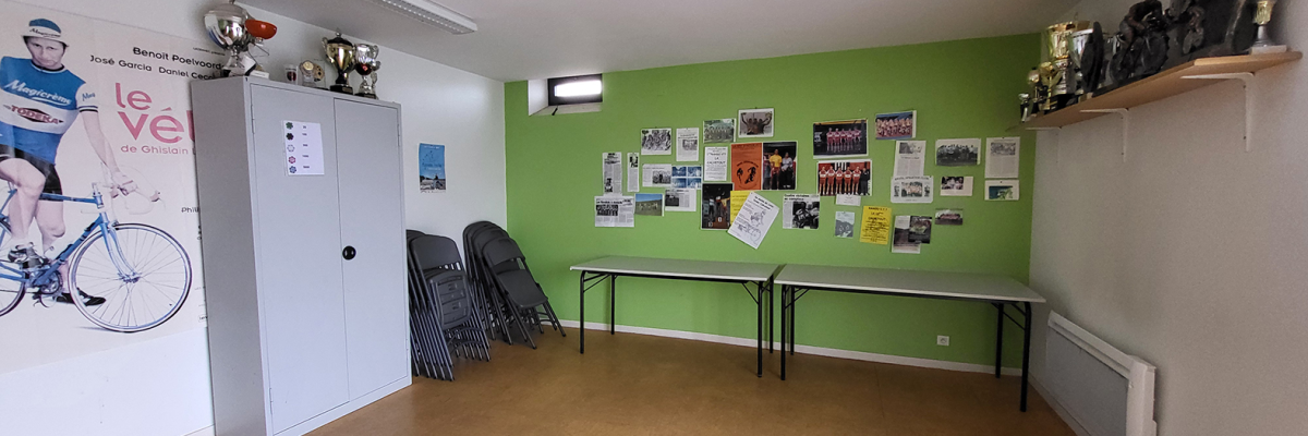 Salle avec tableaux, trophées, affiches, table et chaises.