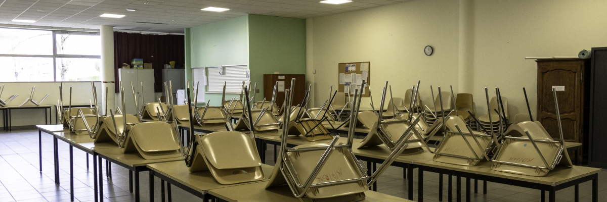 Salle avec tables, chaises et armoire.