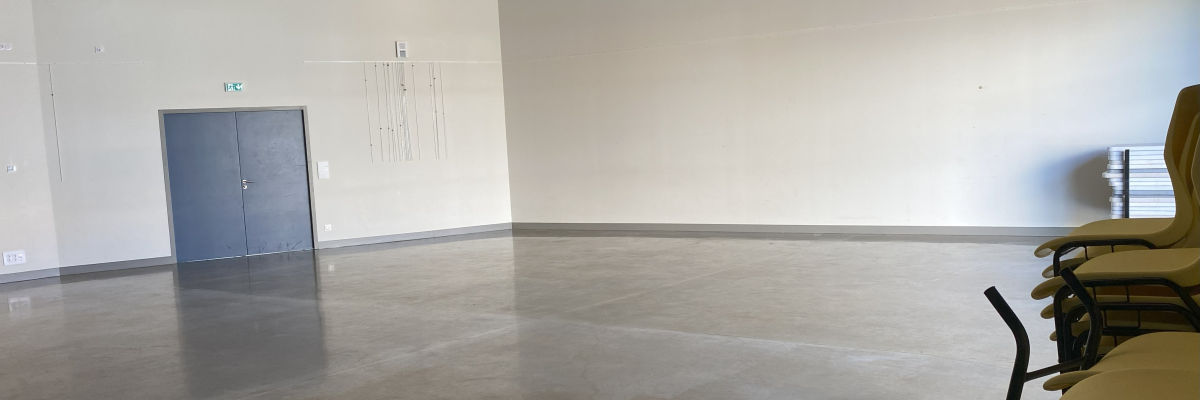 Salle vide avec porte, chaises et éclairage au plafond.