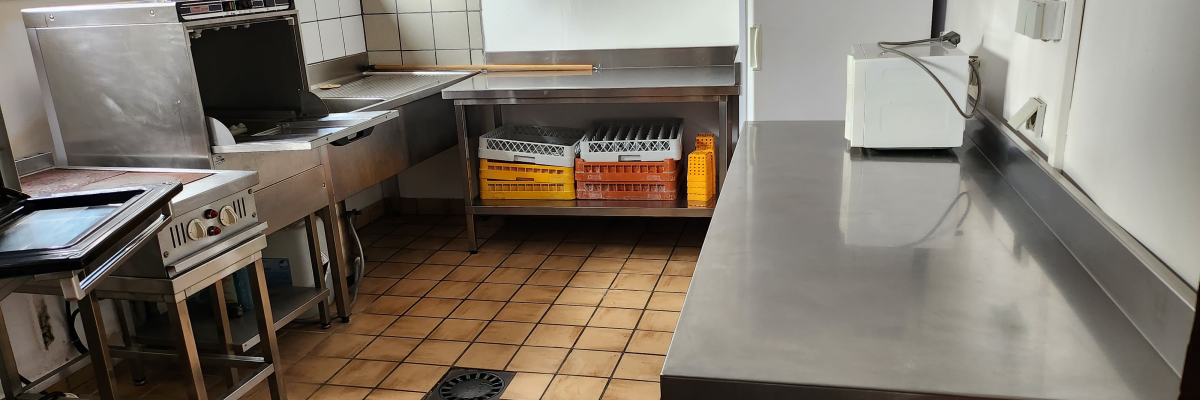 Cuisine équipée: four, plaques de cuisson, évier, réfrigérateur, plan de travail, étagère avec bouteilles.