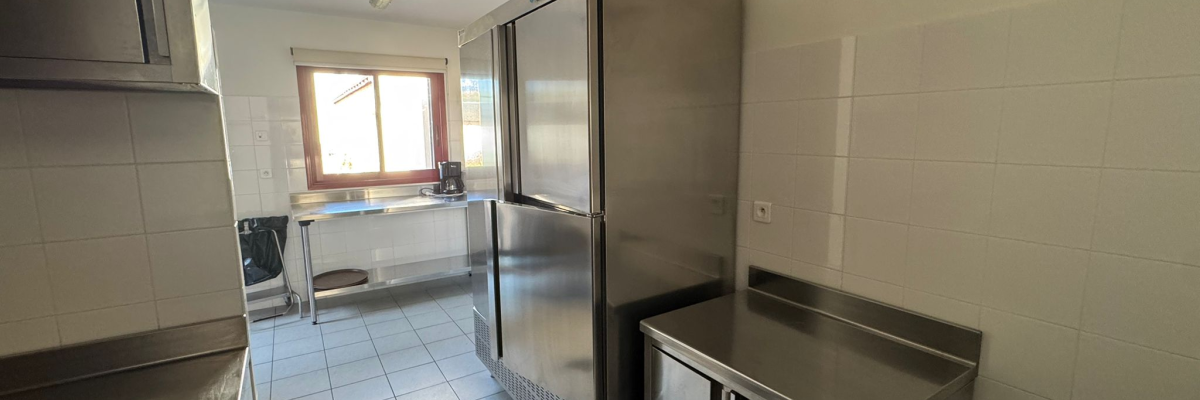 Cuisine avec armoires, frigo, plan de travail et évier.