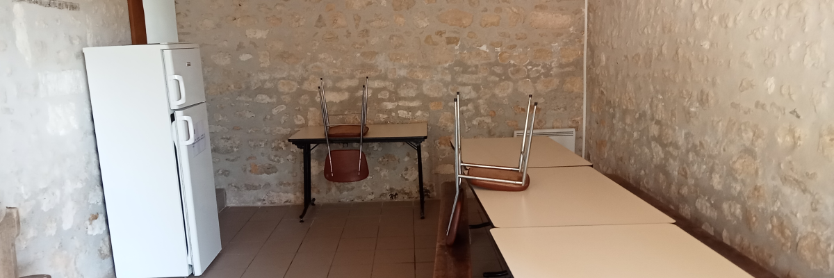 Cuisine avec réfrigérateur, table, chaises et évier.