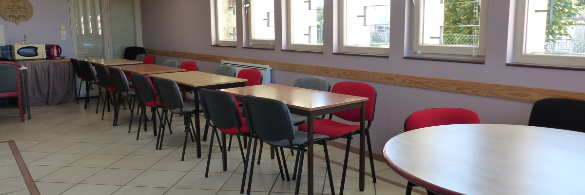 Salle avec tables, chaises, micro-ondes, frigo et distributeur de boissons.