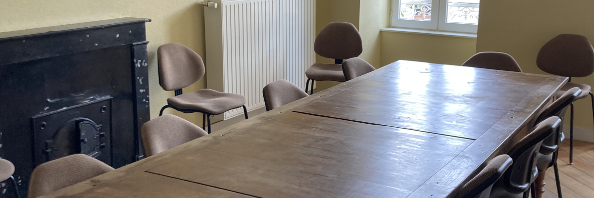 Salle avec cheminée, radiateur, table, chaises et fenêtres.