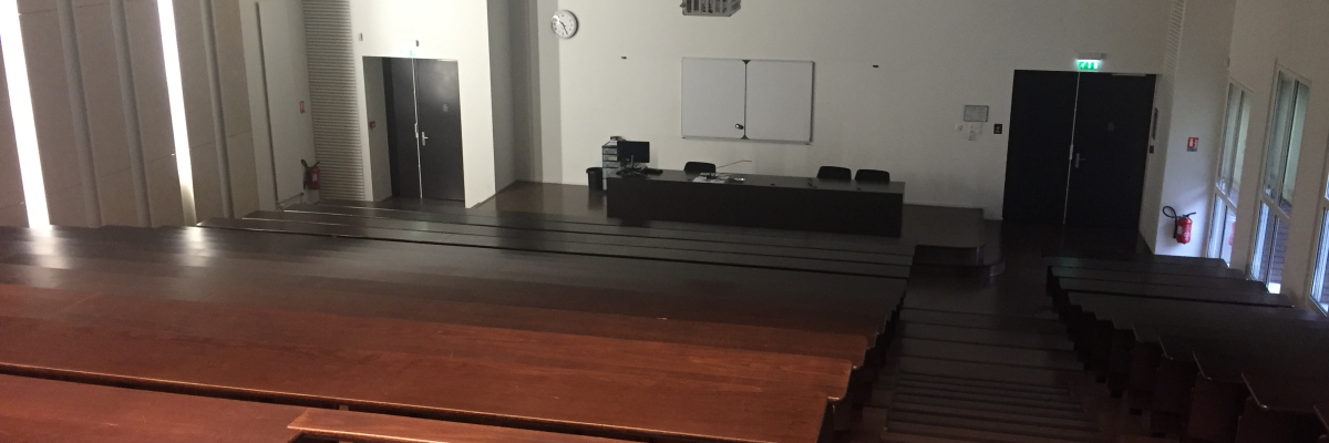 Salle de classe avec tables, chaises, tableau blanc et horloge.