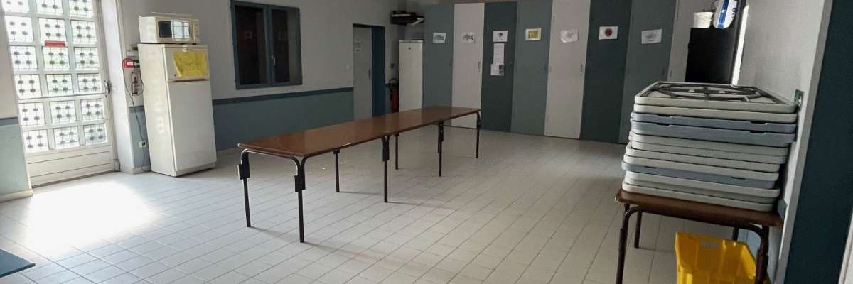 Pièce avec tables, chaises, étagères, porte-manteau, plaques de plâtre, carrelage.