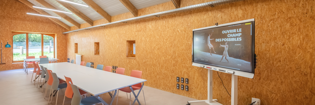 Pièces avec table, chaises, écran, tableau blanc et lumière.