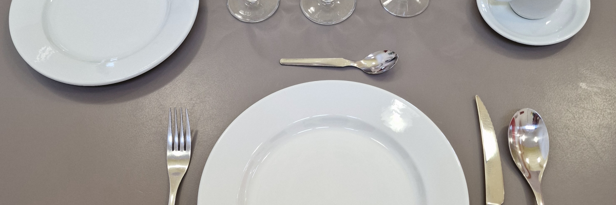 Couverts et vaisselle sur table : assiettes, verres, couverts et tasse.