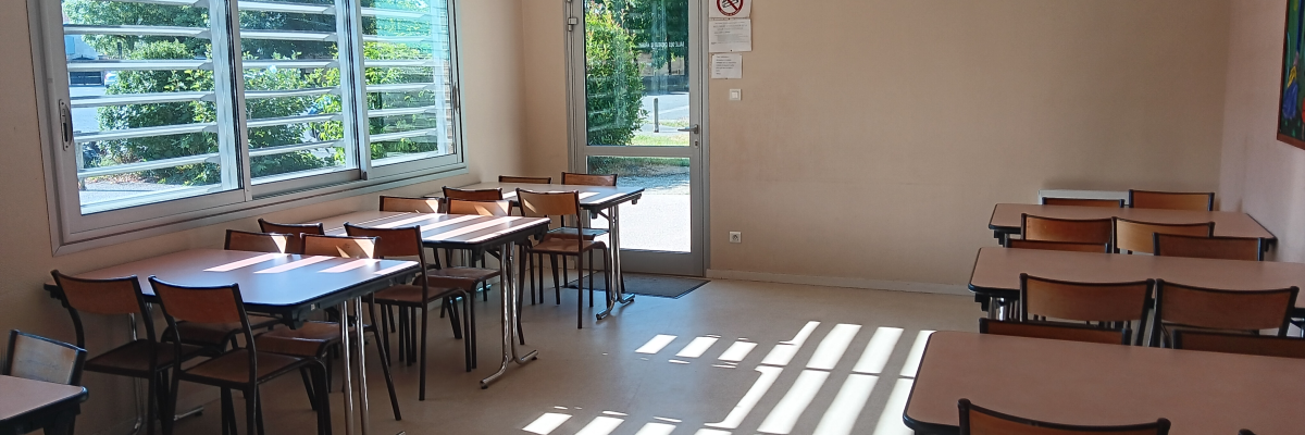 Salle de classe avec tables, chaises, fenêtres et porte.