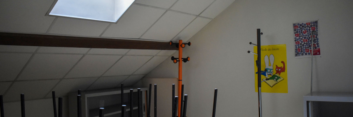 Salle avec tables, chaises, barres parallèles, miroir, affiches et étagères.