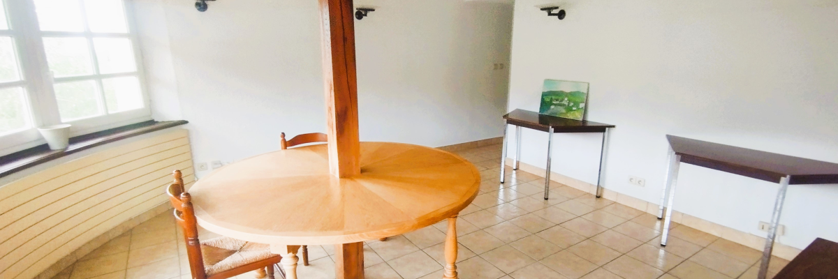 Salle avec table ronde, chaises, tables basses, et distributeur de boissons.