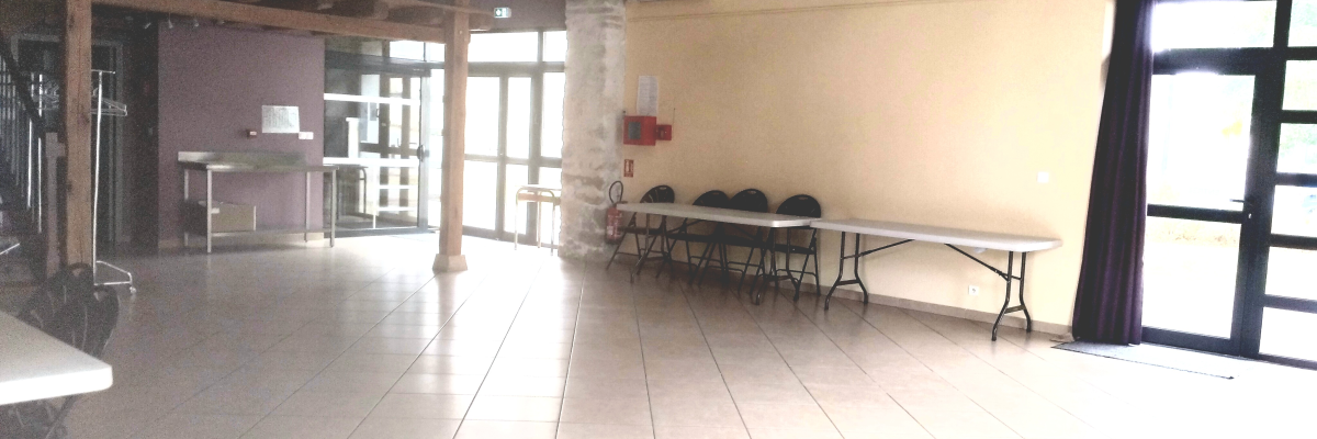 Salle avec tables, chaises, étagères, comptoir, luminaires suspendus et portes vitrées.