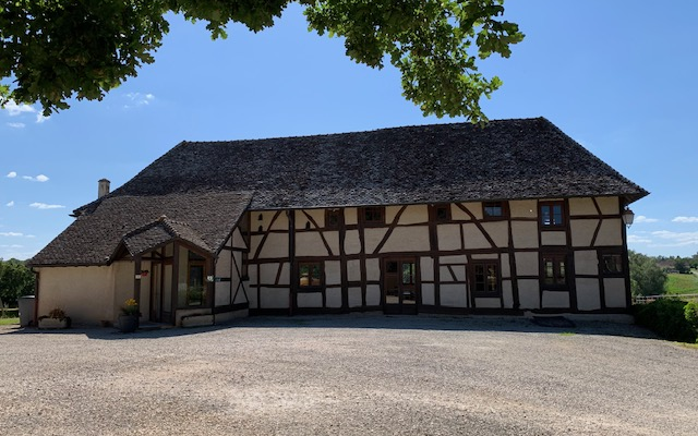Maison à colombages, toit en chaume, entrée, fenêtres, arbre, ciel.