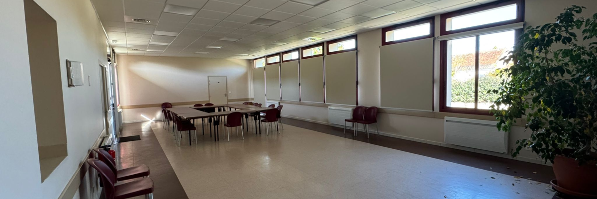 Salle avec tables, chaises, plantes.