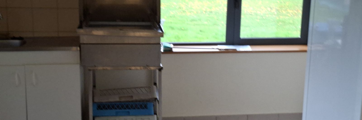 Cuisine avec lave-vaisselle, étagère, table et fenêtre.