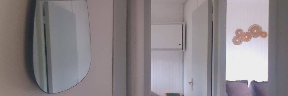 Chambre avec miroir, lit, porte, et interrupteurs.