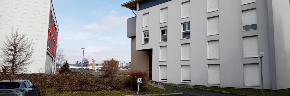 Parking avec voiture, bâtiments et panneaux de signalisation.