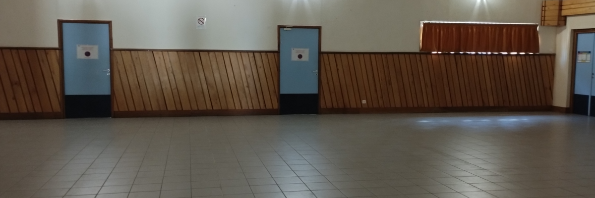 Salle vide avec plancher carrelé, murs en bois, portes et éclairage au plafond.