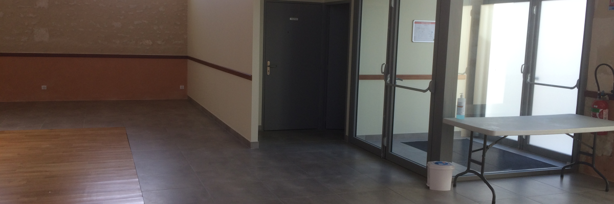 Pièce avec sol en bois, table pliante, porte de salle de bain et fenêtre en arche.