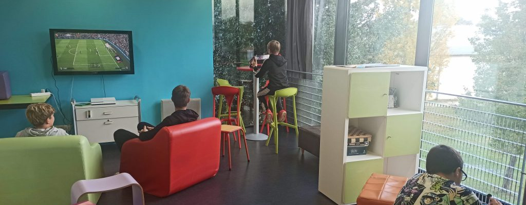 Salle avec canapés, tabourets, téléviseur, étagères, fenêtres.