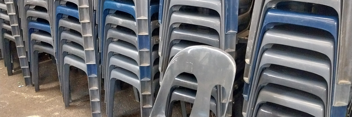 Piles de chaises en plastique empilées dans un entrepôt.