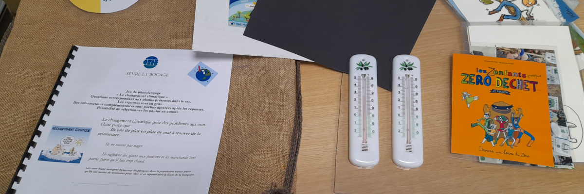 Sur une table, divers documents et objets liés au changement climatique. Inclut un badge, des brochures, un livre, des thermomètres et des feuilles imprimées.