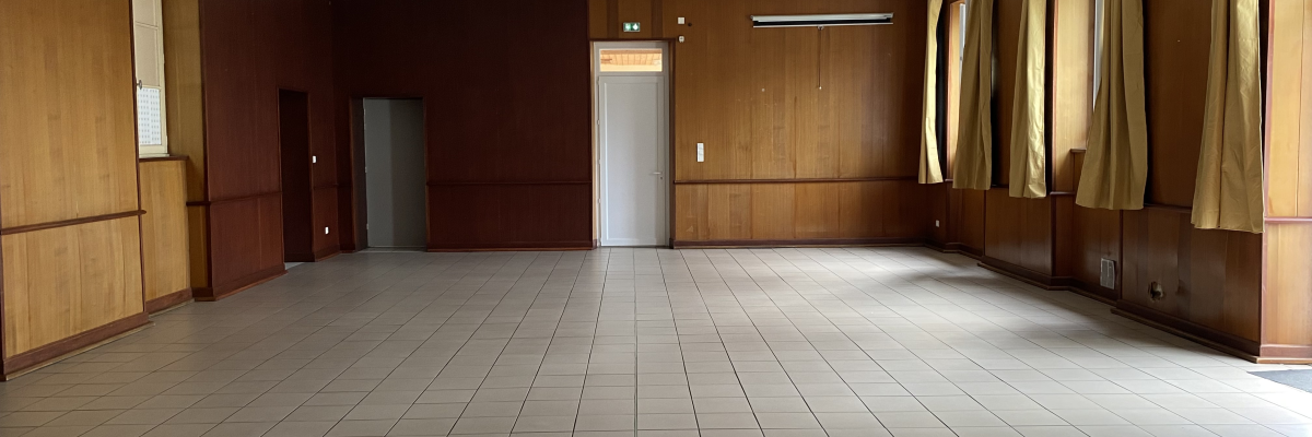 Pièce vide avec sol carrelé, murs en bois, porte et fenêtres avec rideaux.