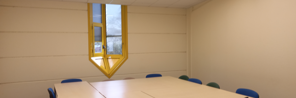Salle avec table, chaises, fenêtre et éclairage encastré.