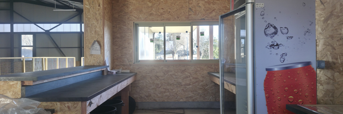 Pièce avec plan de travail, évier, frigo, fenêtre, et murs en OSB.