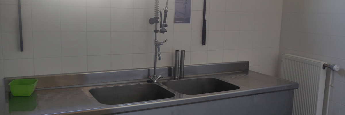 Évier double avec robinet, plan de travail, radiateur et fenêtre.