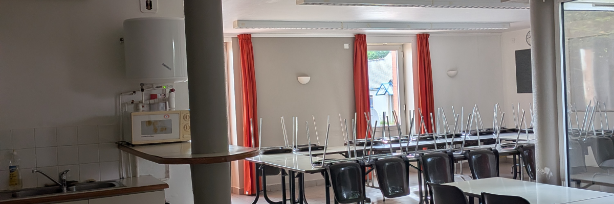 Salle avec table, chaises, rideaux, évier, placards, et luminaire.