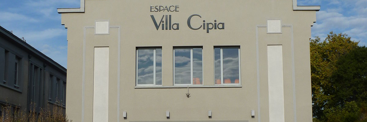 Bâtiment avec façade blanche, trois fenêtres rectangulaires, porte vitrée et escalier extérieur.
