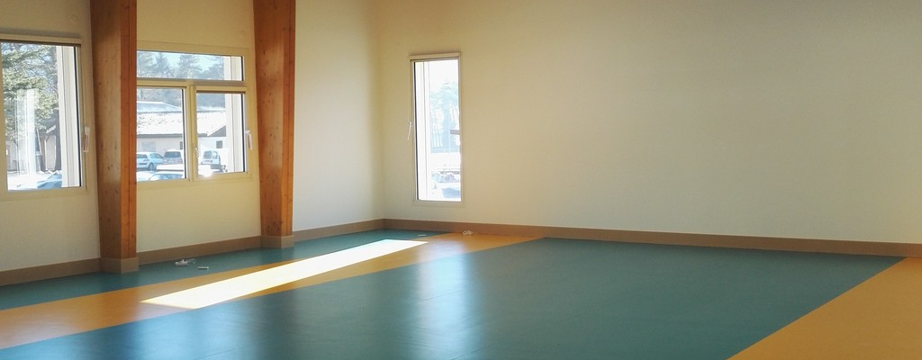 Salle avec sol coloré, fenêtres et éclairage plafonnier.