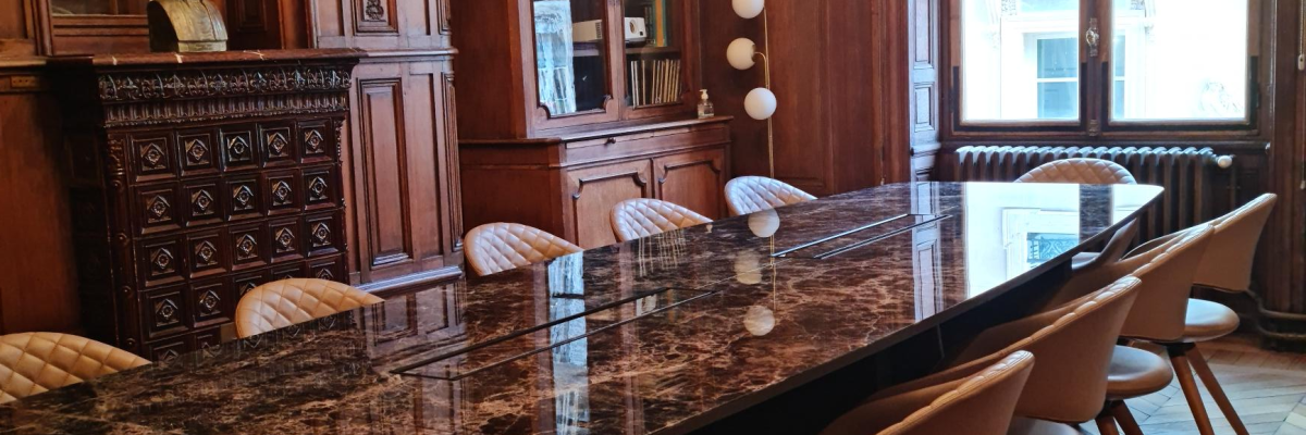 Salle à manger avec table en marbre, chaises, buffet et lustre.