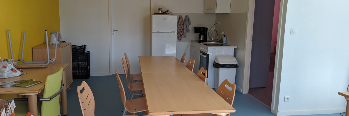 Cuisine avec table, chaises, réfrigérateur, évier et placards.