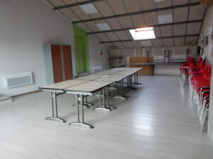 Salle avec tables, chaises, lumière naturelle et radiateur.