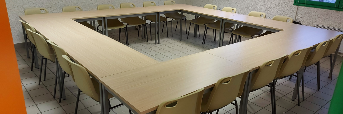 Salle de réunion avec grande table et chaises.