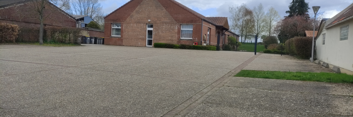 Parking avec bâtiments, arbres et poubelles.