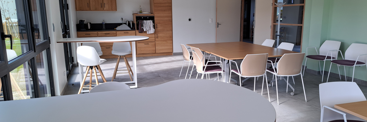 Salle avec tables, chaises, cuisine et armoires.