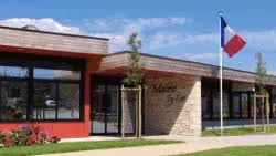 Bâtiment extérieur avec façade en briques et verre, drapeau français, pelouse et arbre.