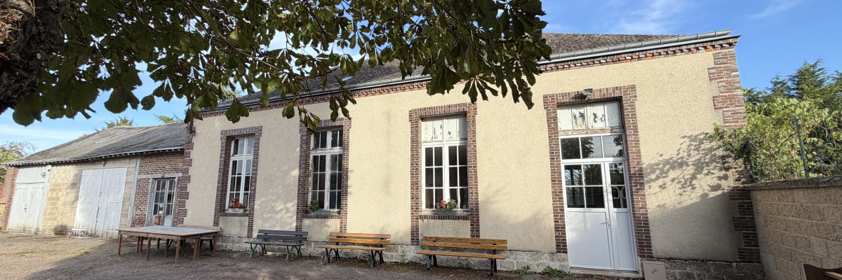 Bâtiment avec fenêtres, portes, bancs et tables en extérieur.