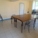 Pièce avec table, chaises, balai et porte ouverte.