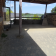 Terrasse en béton avec vue sur paysage, murs en pierre et brique, toit en bois.