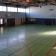 Salle de sport avec paniers de basket, terrains de jeu, bancs et portes.