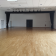Salle vide avec parquet, éclairages suspendus, portes et extincteurs.