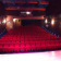 Salle de cinéma avec sièges, projecteur, éclairage et scène.