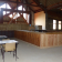 Salle avec tables, chaises, comptoir en bois, étagères et fenêtres.